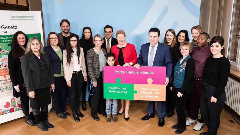 Das Bild zeigt Dr. Franziska Giffey und Hubertus Heil mit mehreren Menschen vor einer Fotowand