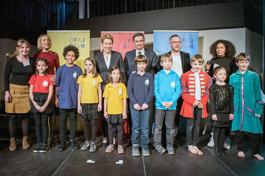 Das Bild zeigt Dr. Franziska Giffey auf einer Bühne stehend, vor ihr eine Reihe von Kindern