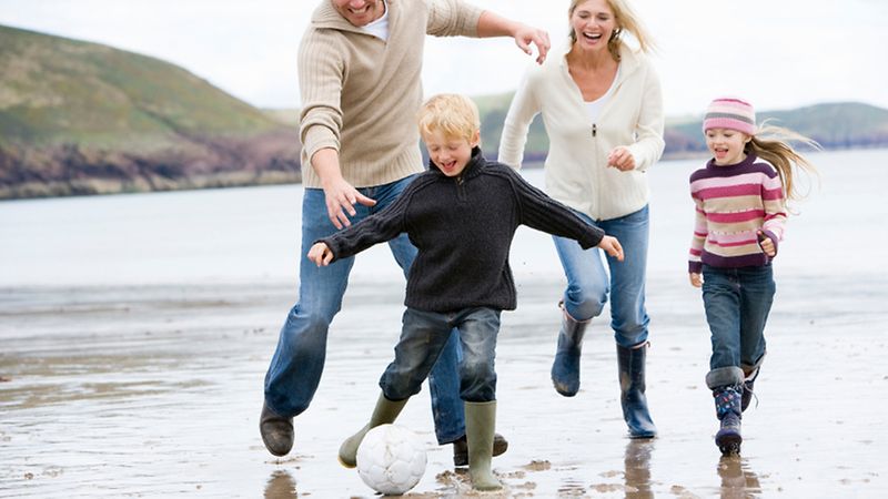 Porträt einer spielenden Familie am Strand