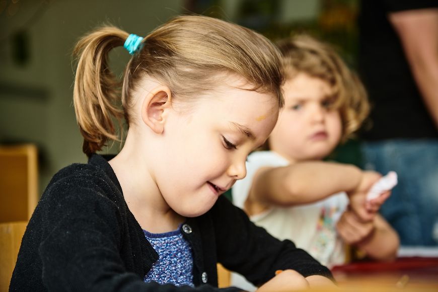 Zwei Kinder sitzen an einem Tisch und malen.