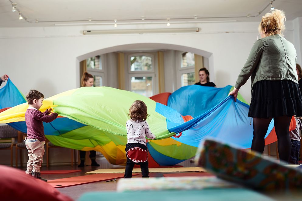 Frauen und Kinder spielen mit großen Tüchern