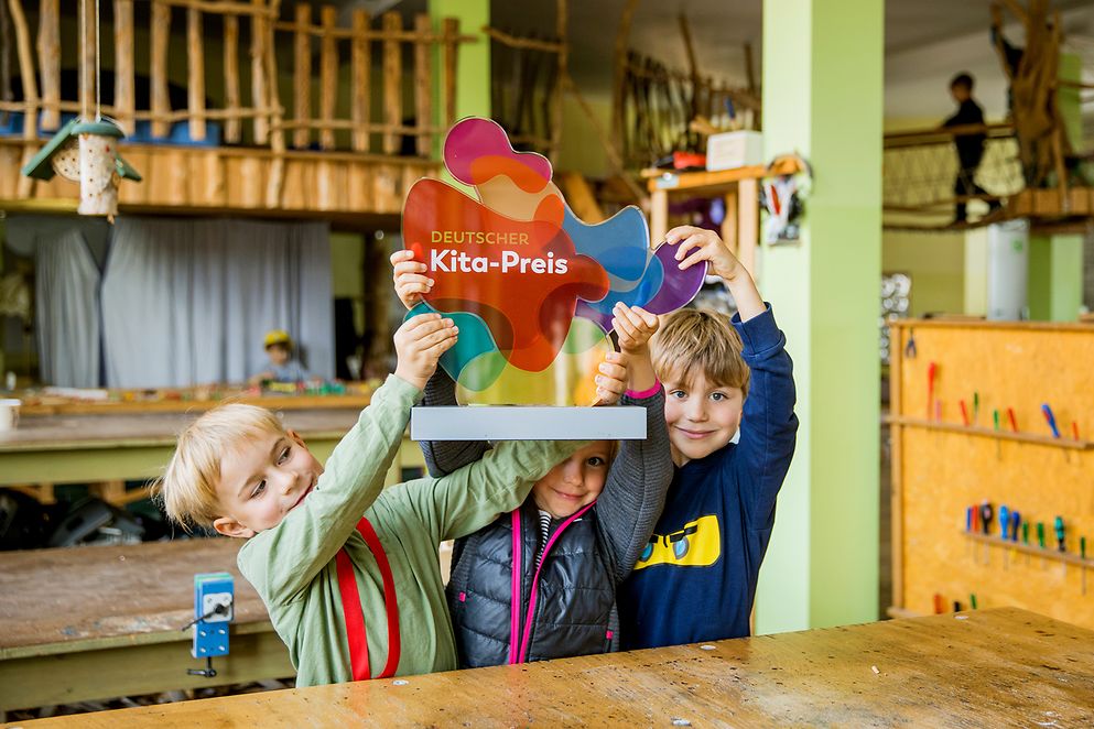 Kinder halten ein Schild "Deutscher Kita-Preis" hoch