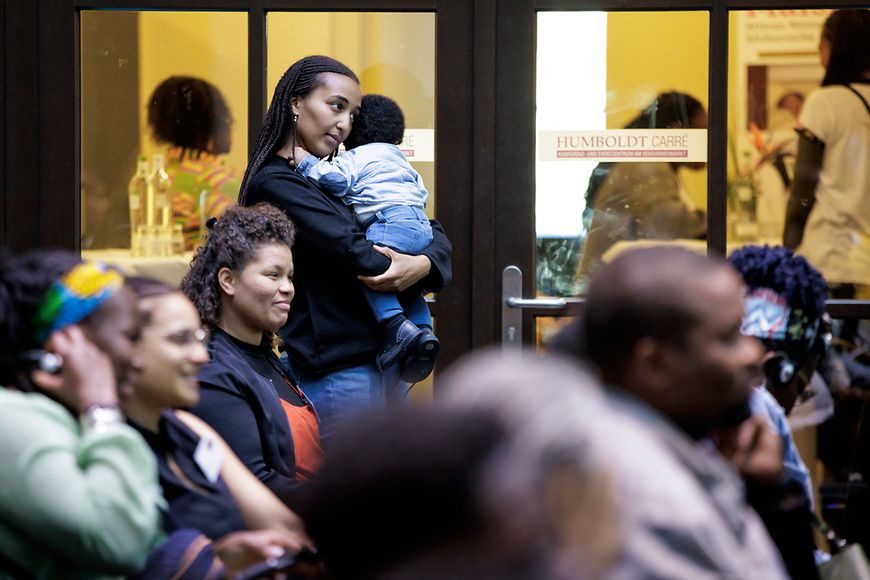 Frau im Publikum hält ein Baby im Arm