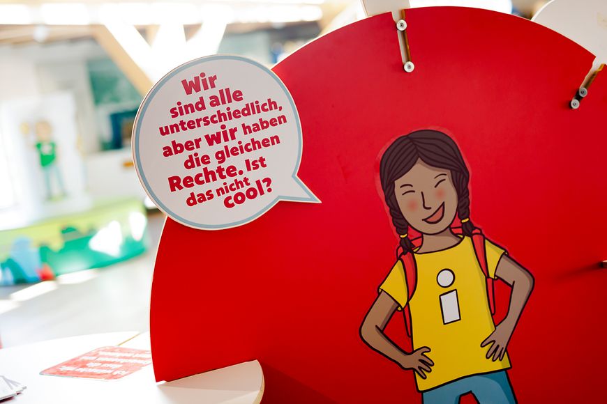 Ein Modul der Ausstellung, auf dem ein Mädchen mit einer Sprechblase auf rotem Hintergrund gezeichnet ist