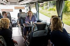 Lisa Paus sitzt in einem Bus und unterhält sich mit weiteren Fahrgästen