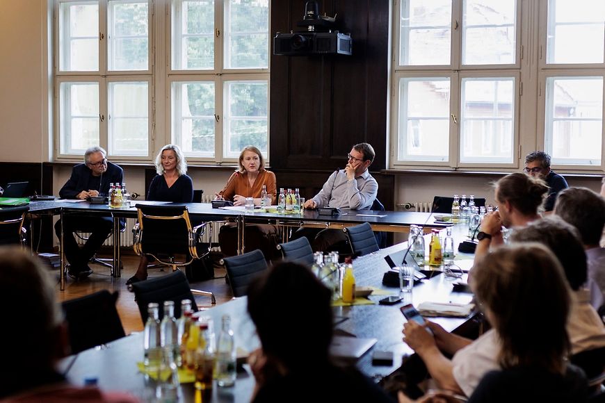 Lisa Paus sitzt mit anderen auf einem Podium und diskutiert