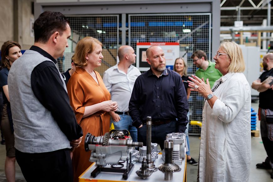 Lisa Paus unterhält sich mit Mitarbeitenden in einer Werkshalle