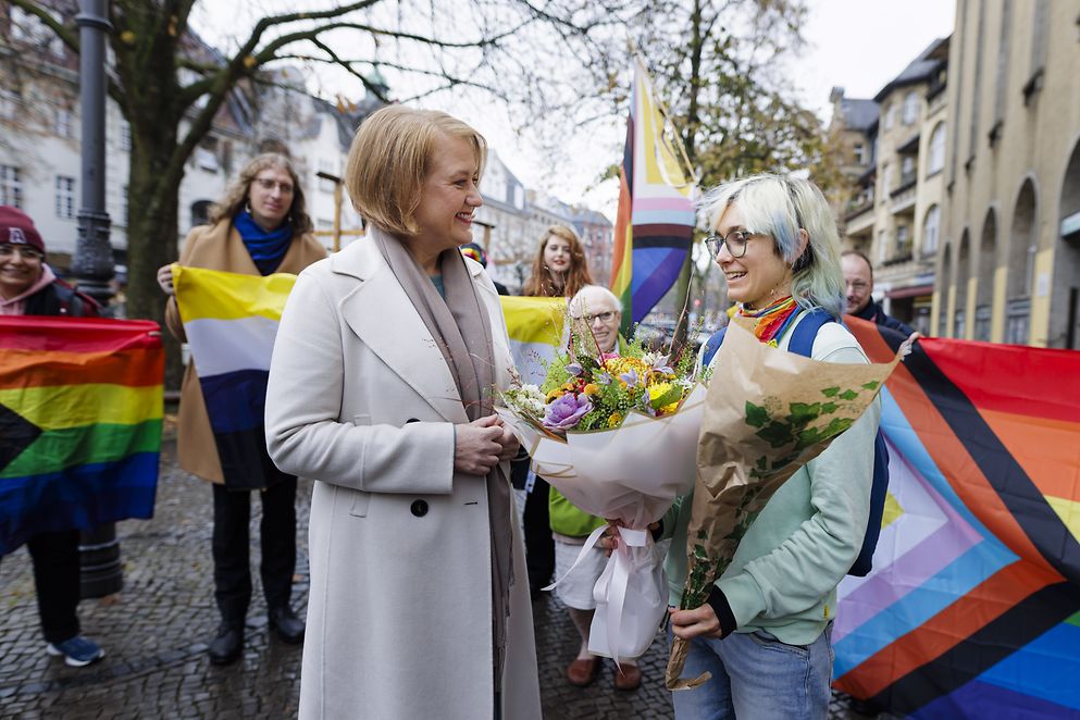 Lisa Paus übergibt im Standesamt einen Blumenstrauß an eine Person