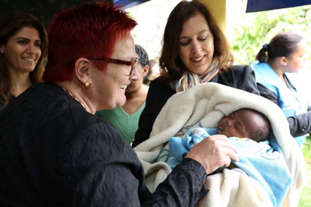 Elke Ferner im Gespräch mit einer jungen Mutter, die ihr Baby auf dem Arm trägt