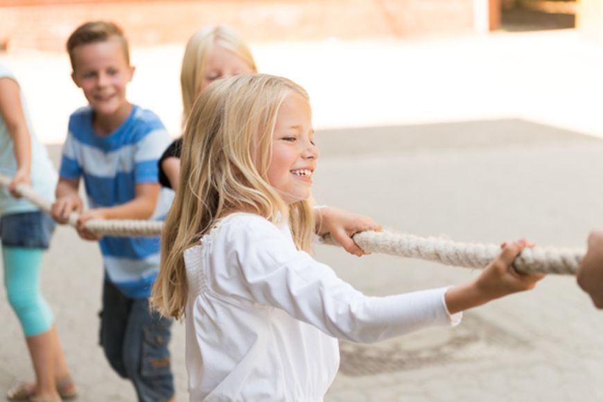 Lachende Kinder ziehen an einem Seil